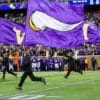 people running and holding Minnesota Vikings flags in green field