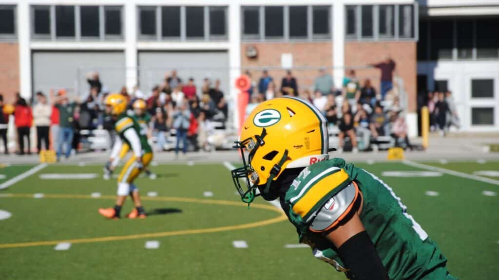 High school football game with players in action and audience in the background in Toronto.