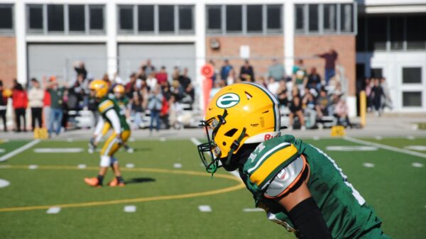 High school football game with players in action and audience in the background in Toronto.