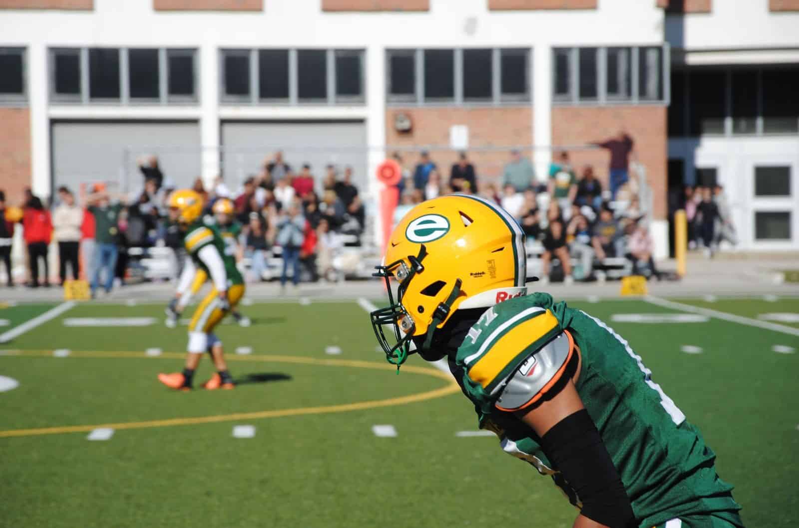 High school football game with players in action and audience in the background in Toronto.